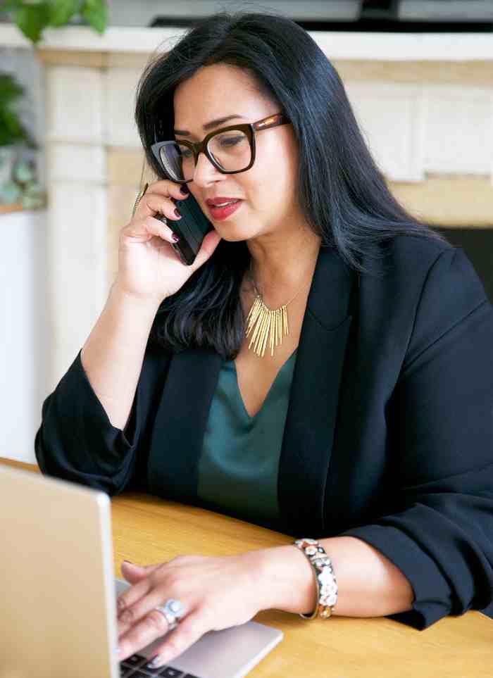 A woman speaking on the phone, looking at her computer