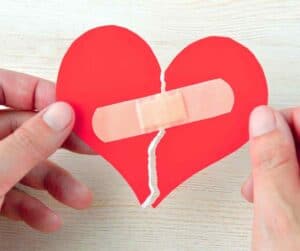 A red paper heart ripped in two, stuck together with a plaster.